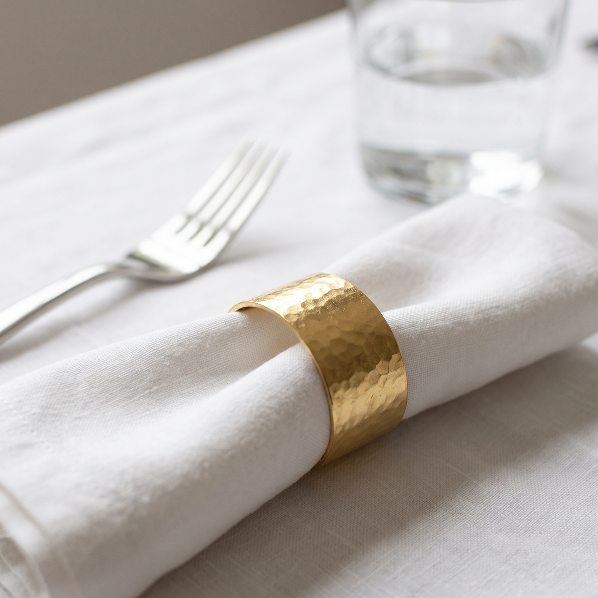 Rond de serviette en métal doré sur une serviette en lin blanc