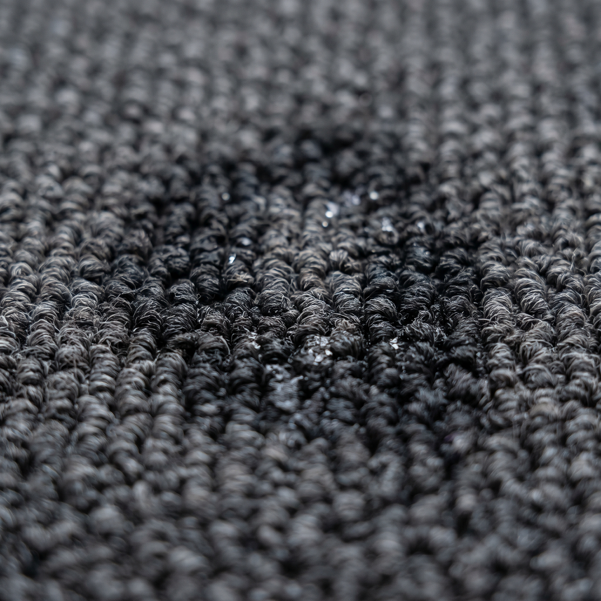 Gros plan de gouttes absorbées par un tapis d'entrée