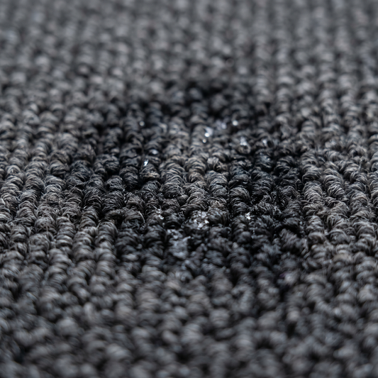 Gros plan de gouttes absorbées par un tapis d'entrée
