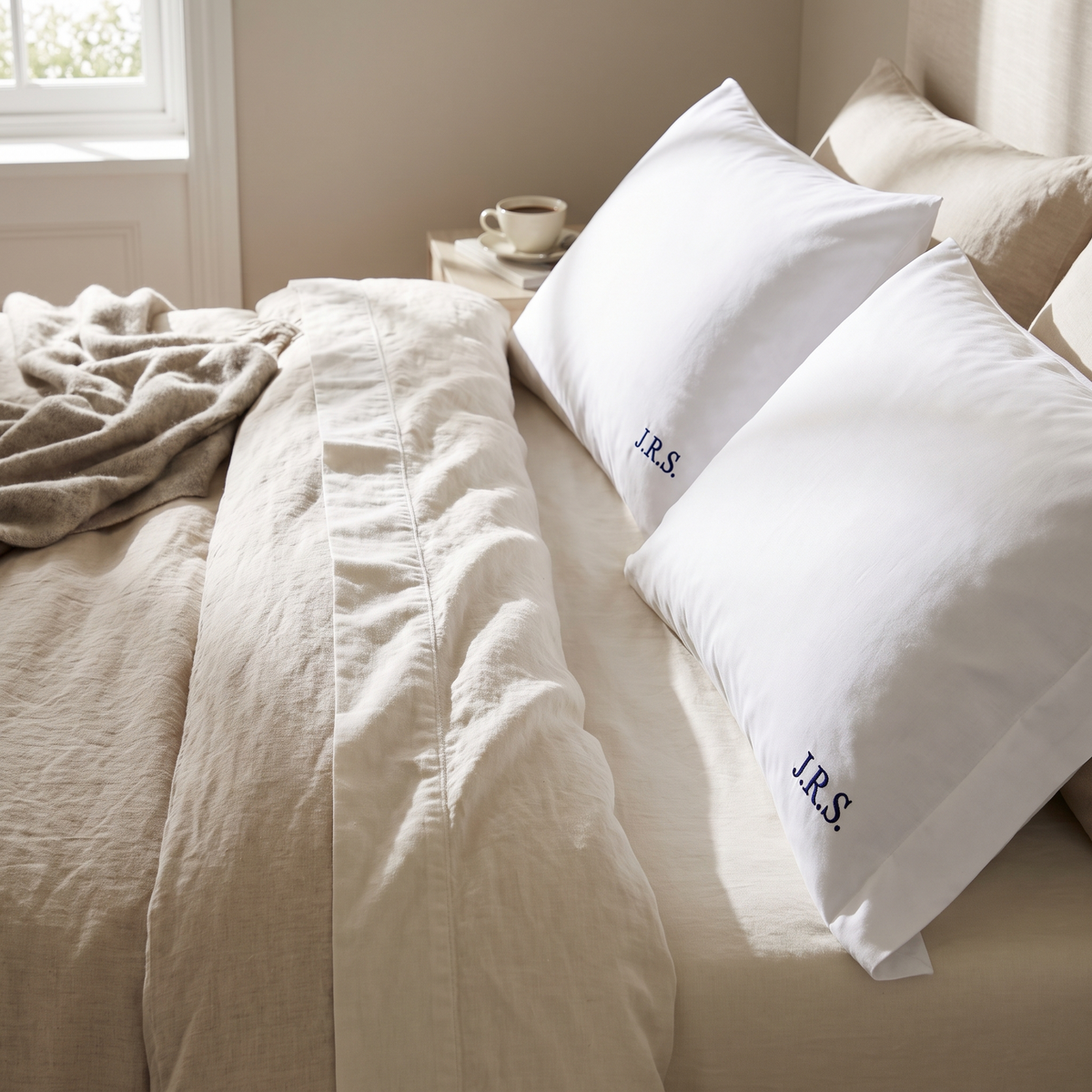 Deux taies d'oreiller brodées d'un monogramme sur un lit fraîchement fait