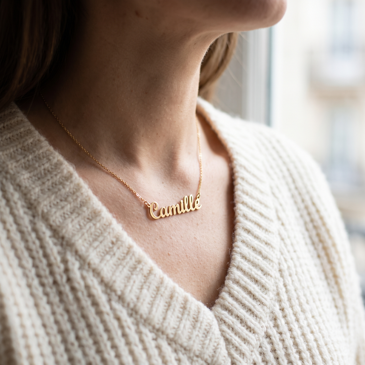 Collier au prénom porté à la clavicule sur un chandail de tricot crème